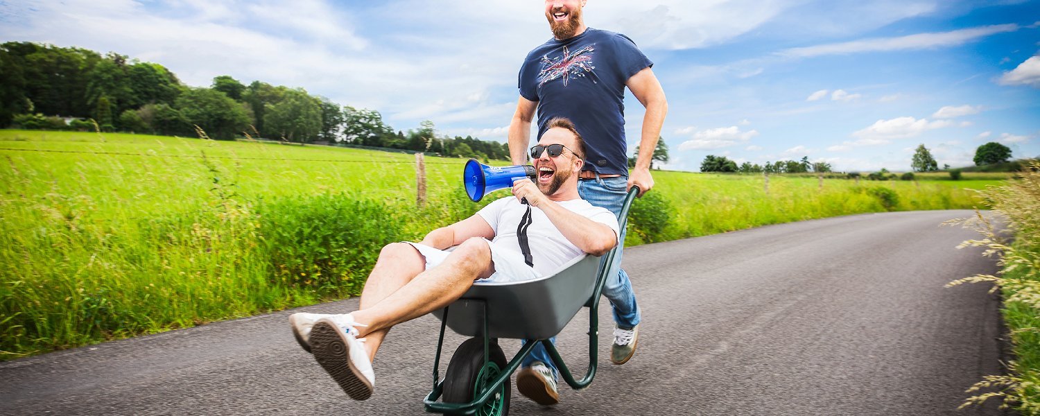 Ein Mann schiebt einen anderen Mann in einer Schubkarre